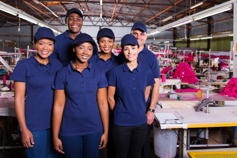 A production team in matching navy uniforms standing together on the factory floor